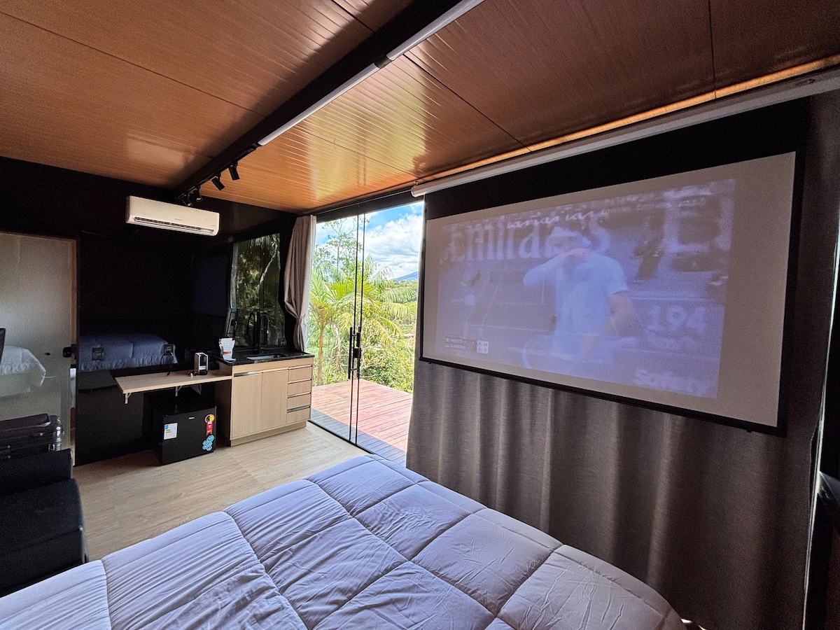 Visão geral do interior com cozinha, projetor e cama