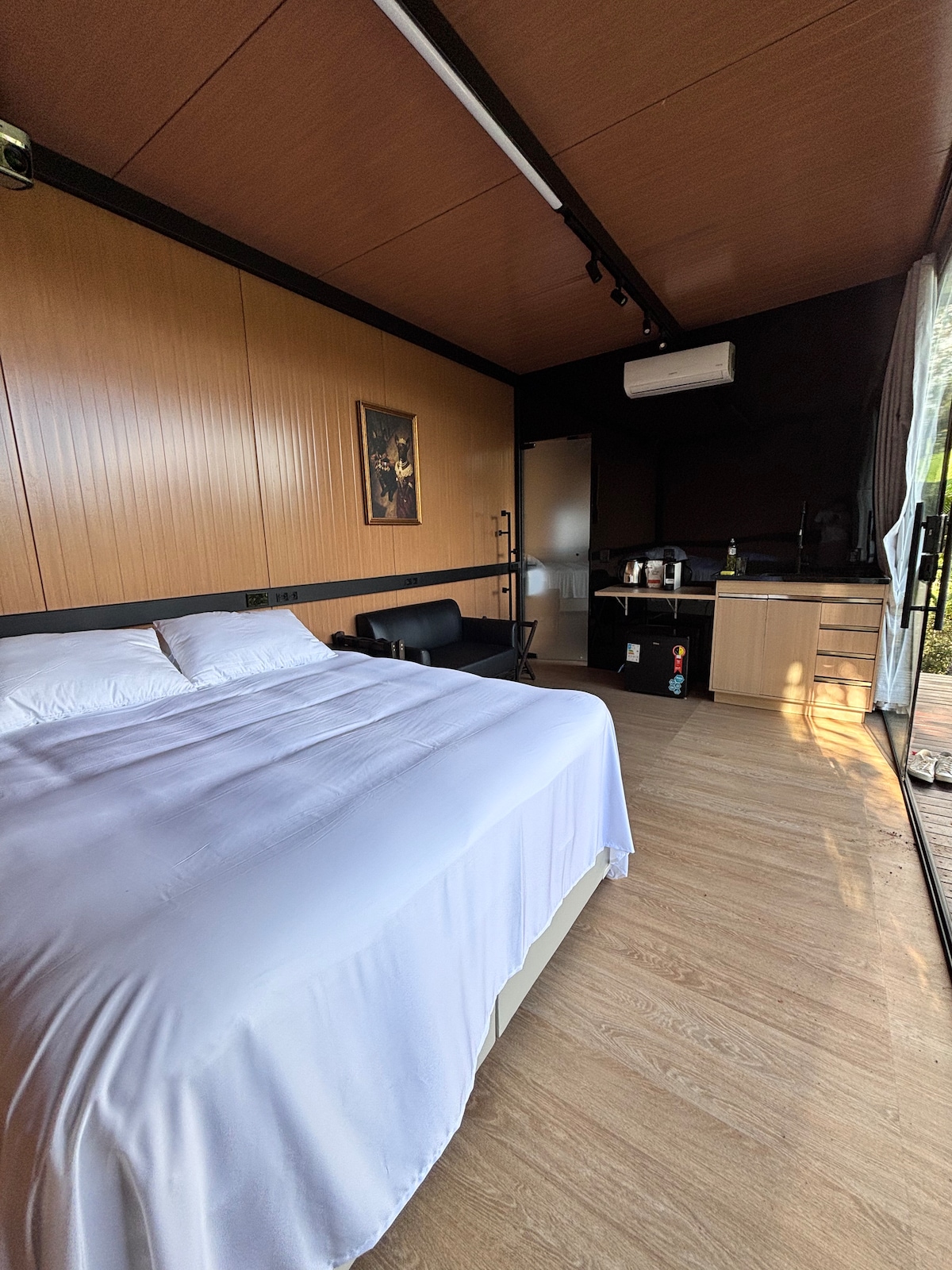 Quarto inteiro com cama queen, cozinha e painéis de madeira