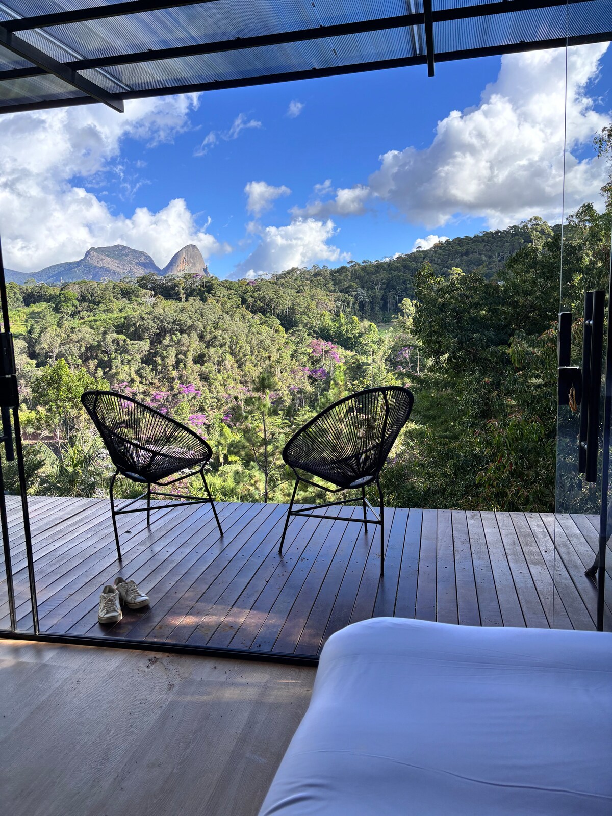 Vista do deck com cadeiras e cama em primeiro plano