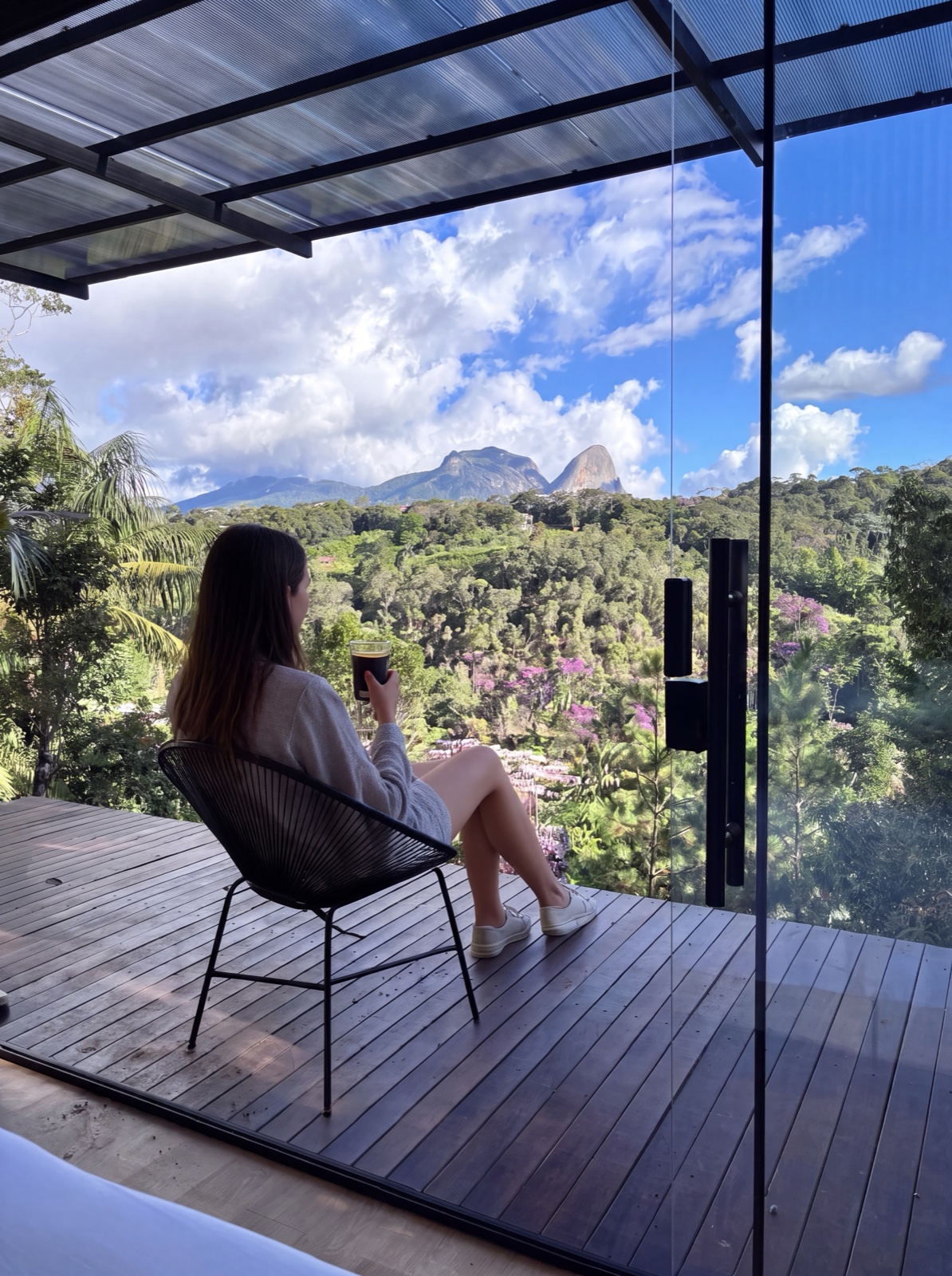 Mulher tomando um café no deck do Chalé Vista com vista para a Pedra Azul