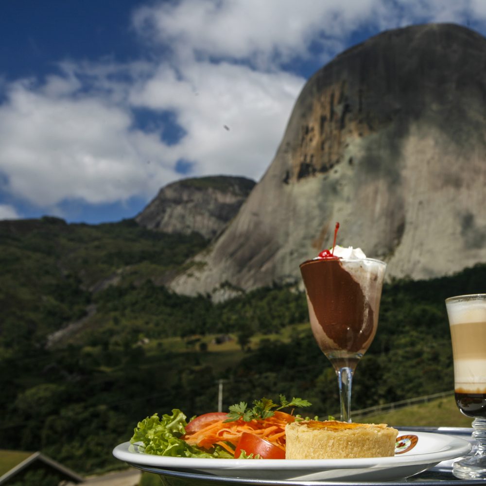 Prato e café servidos com a Pedra Azul ao fundo